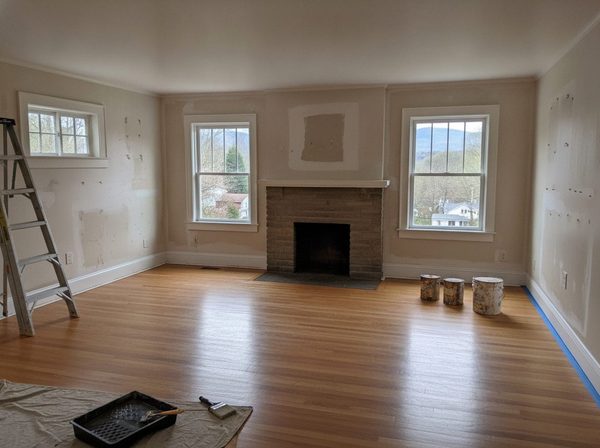 Empty living room with patched drywall and a ladder before painting